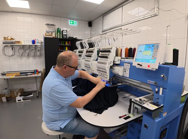 Medewerker stelt de borduurmachine af bij een borduurring
